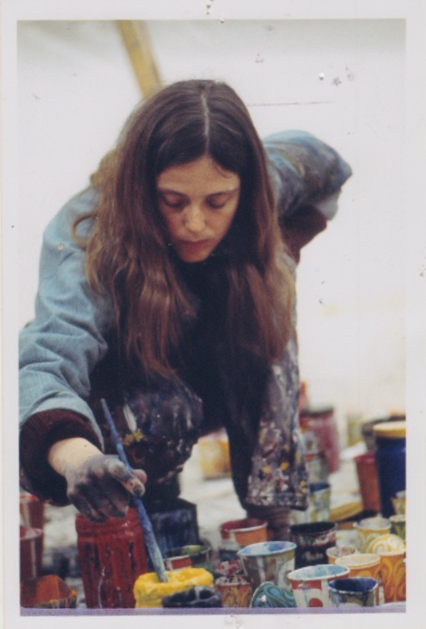 photo of a woman leaning over mixing paint