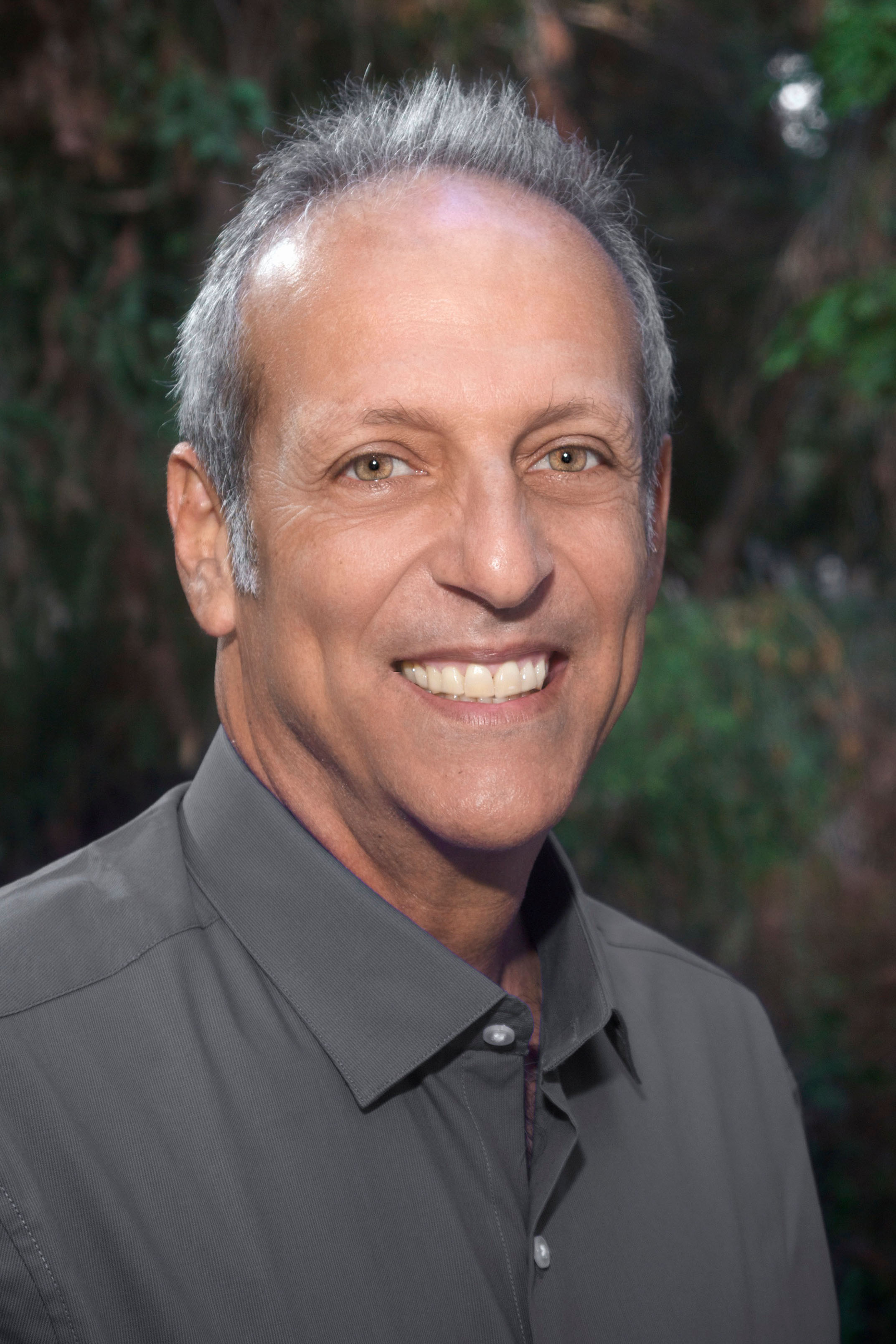 Photo of a man smiling, dressed in a button-up shirt.