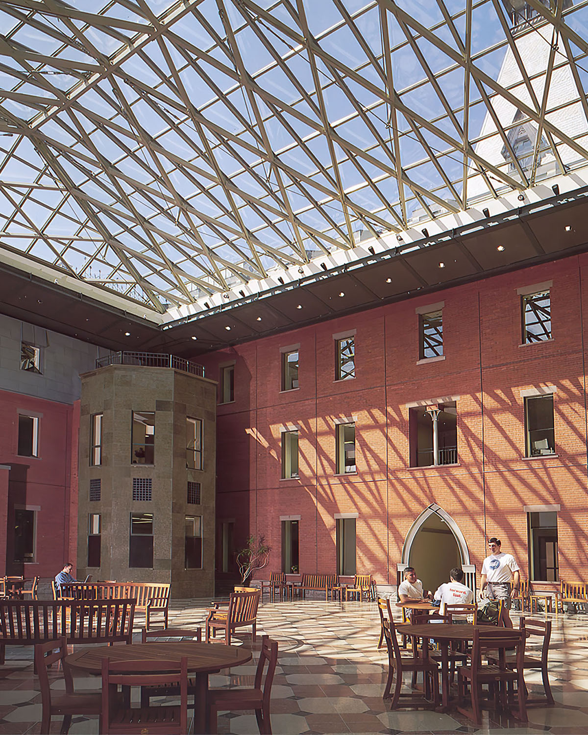 A glass roof covers an atrium with tables and benches for gathering and studying.