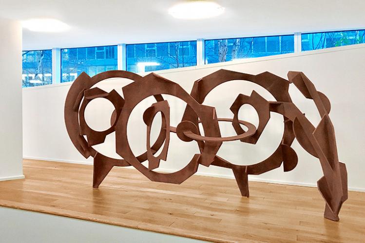 large sculpture of bronze circles on a wooden floor 