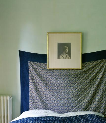 image of a photograph hung over a sheet on a wall above a bed
