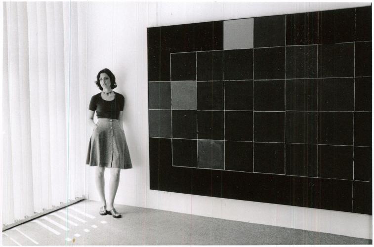 woman standing next to a large painting