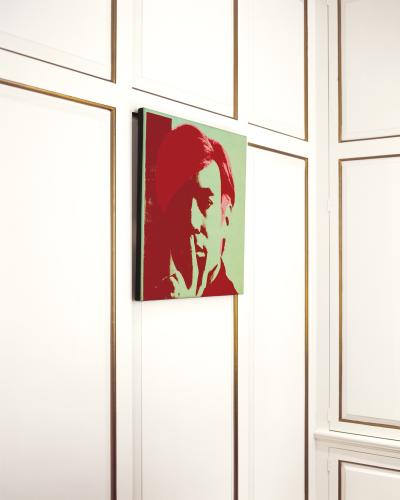 An interior angle of a red and green Andy Warhol portriat on the wall