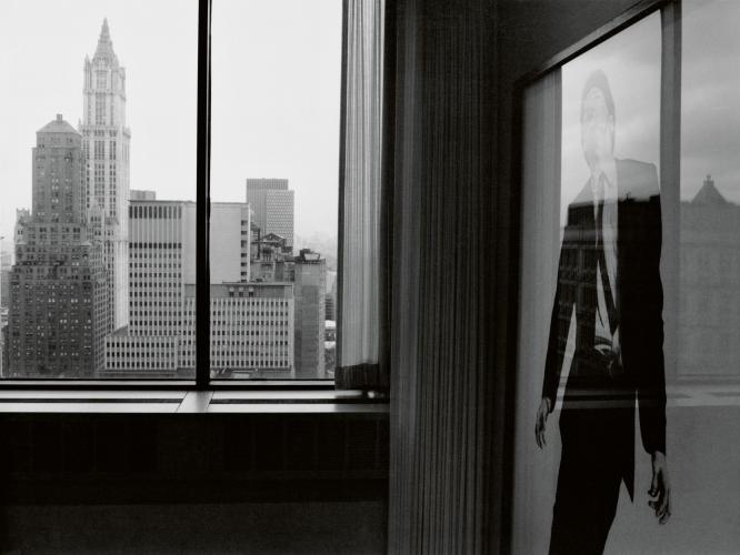 image of the inside of a building with a Robert Longo photograph on one side and a window overlooking cities on the left