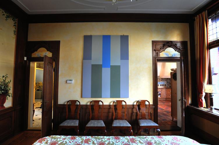 painting installed in a dining room with grand doors and windows