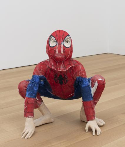 a sculpture of a small person in a spiderman outfit looking up crouching down