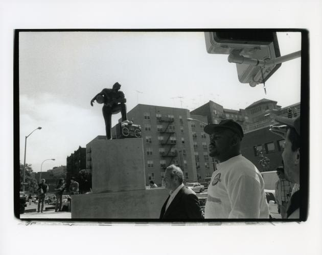 black and white photo of people looking at a sculpture on a pedestal outside