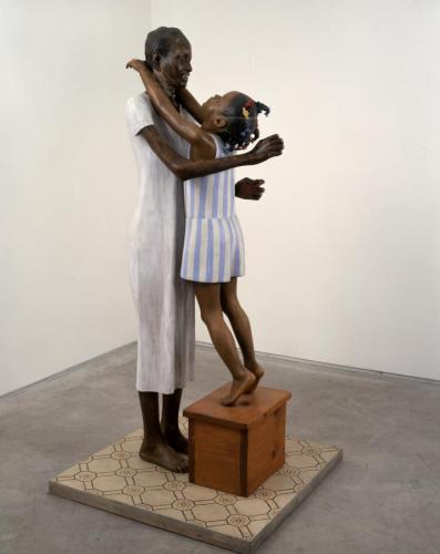 sculpture of a woman and a young girl standing on a box embracing