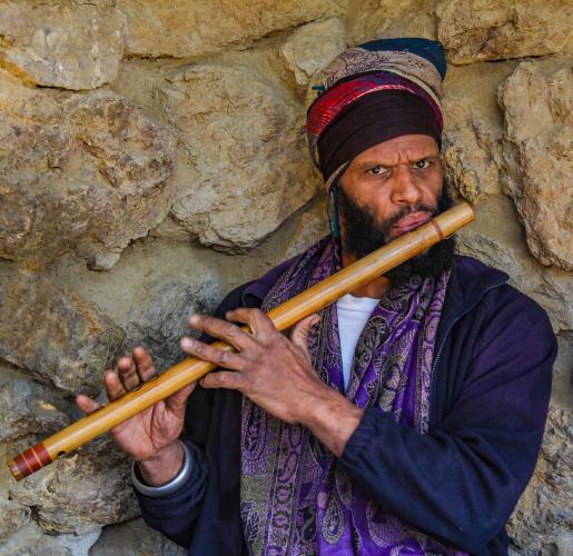 A man plays a long woodwind instrument made of a natural material