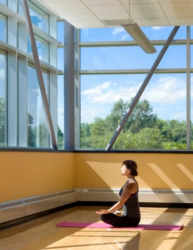 Brightly lit room with large windows and woman sitting on a yoga mat