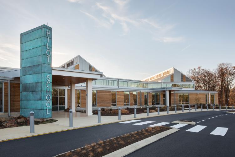 Exterior of single floor building with tall rectangular turquoise pillar with the words Pilot School.