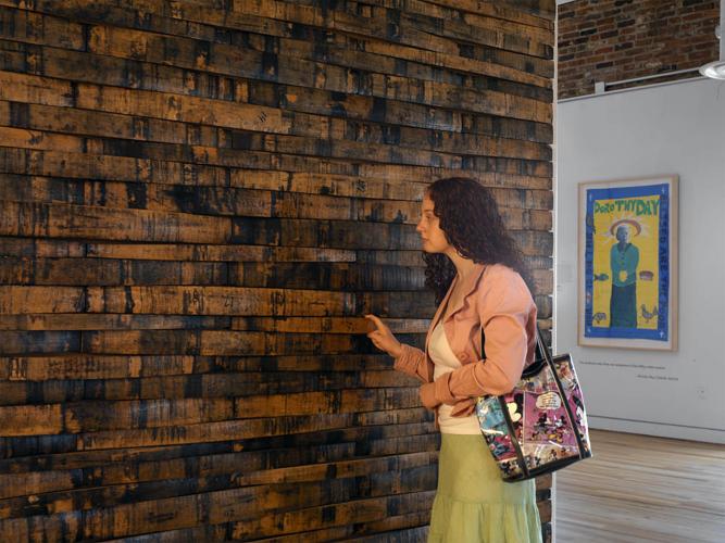 A woman looks closely at a wall made of recycled whiskey barrels