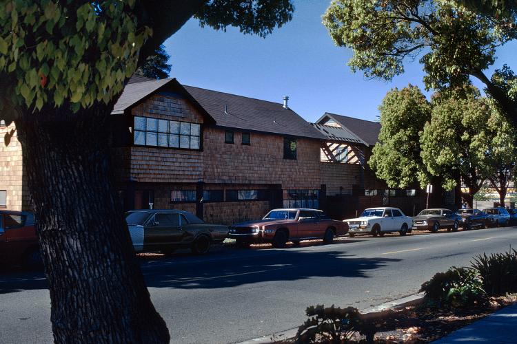 Parked cars line the street in front of a house