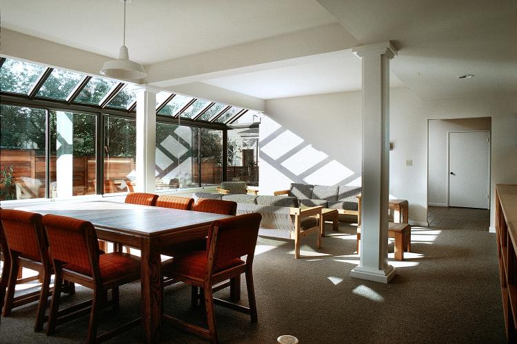 Living room with a meeting table, two couches, and a glass wall facing outside.