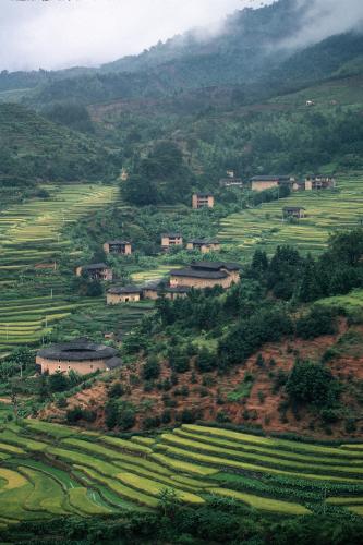 Aerial view of Fujian landscape with lush green landscape and round tan houses.