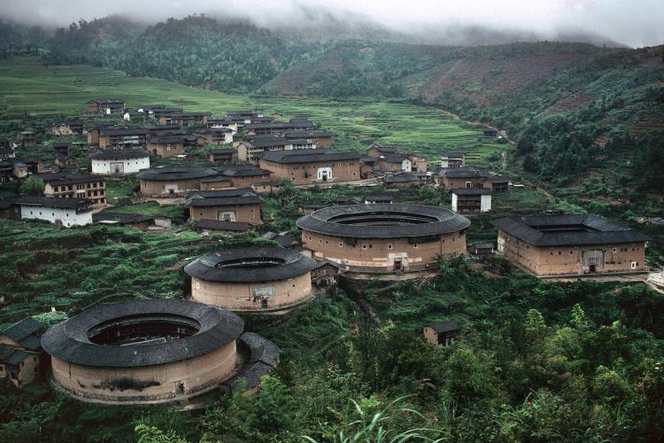 Aerial view of Fujian landscape with lush green landscape and round tan houses.