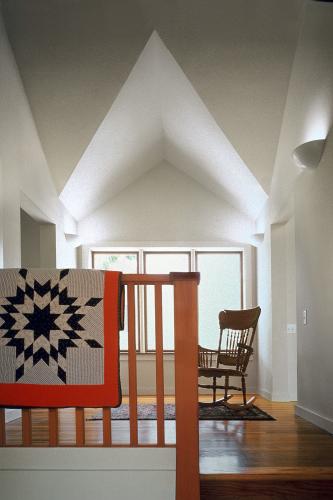 A small stairway landing contains a rocking chair and throw rug. 