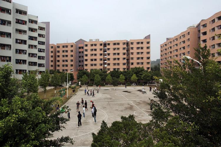 View of grey and brick-colored dorm building exteriors and basketball court.