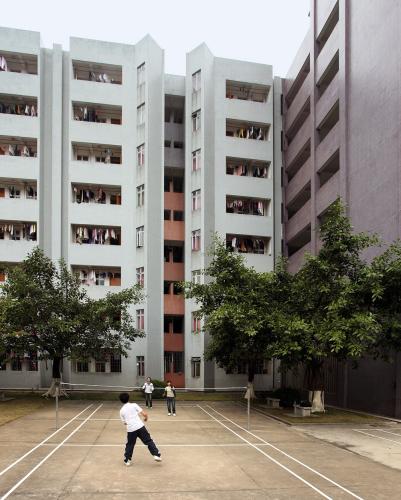 Multistory apartment building facing basketball court in courtyard.