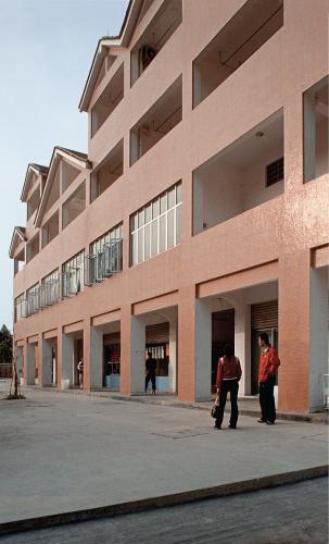 Two people stand outside a four-story apartment building.