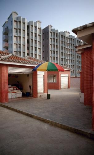 A patio umbrella stands outside a kiosk building.