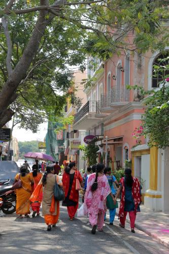 Women in colorful saris walk down the street.