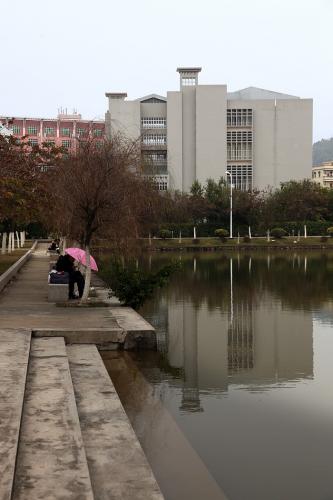 A pool of water reflects a four-story building at its far end. 