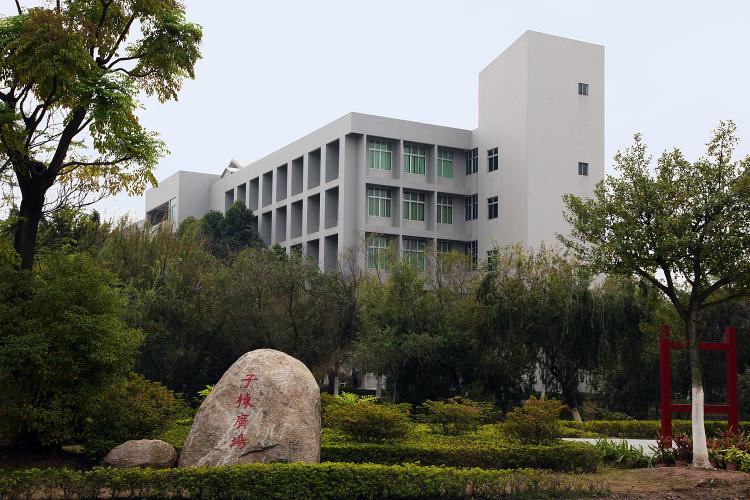 Exterior view of the east side of a rectangular building with a tall, rectangular tower. Many windows line the building's walls, creating a grid-like design. 