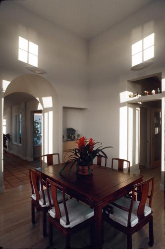 Six wooden chairs surround a rectangular table decorated with a vase of flowers.