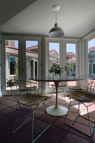 A table and wire frame chairs face glass doors leading to the courtyard.