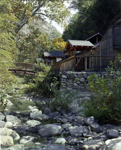 A wooden bridge crosses a creek, providing a path to the bath house.