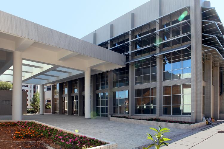 Exterior of a glass-walled building and entry forecourt. 