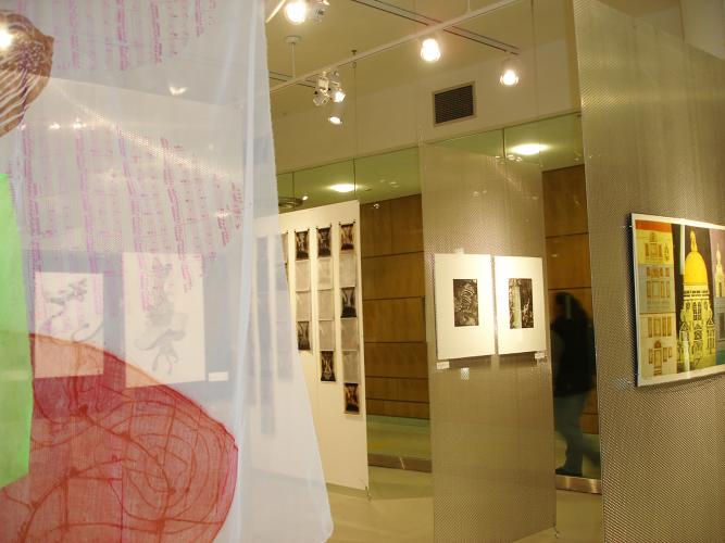 Art prints are displayed on translucent panels hanging from the ceiling. 
