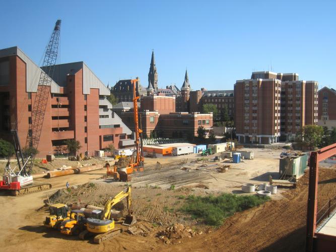 A construction site is set up outside of several red brick buildings.