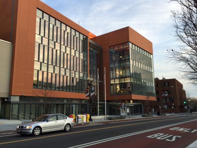 Red brick frames a rectangular glass wall on the exterior of multistory building.