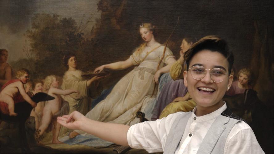 A smiling teenage girl points toward a painting in an art museum.