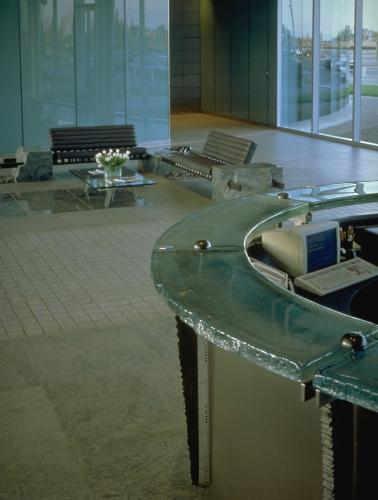 A circular desk with a glossy counter overlooks benches in a lobby. 