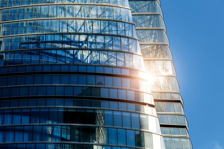 Closeup view of a transparent skyscraper reflecting sunlight.