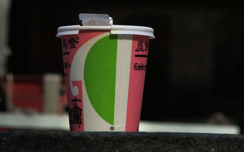 A green, white, and red paper cup with black Chinese characters.