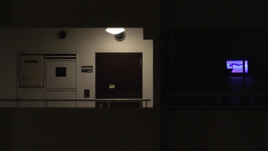 View of an apartment door lit by an overhead light at night