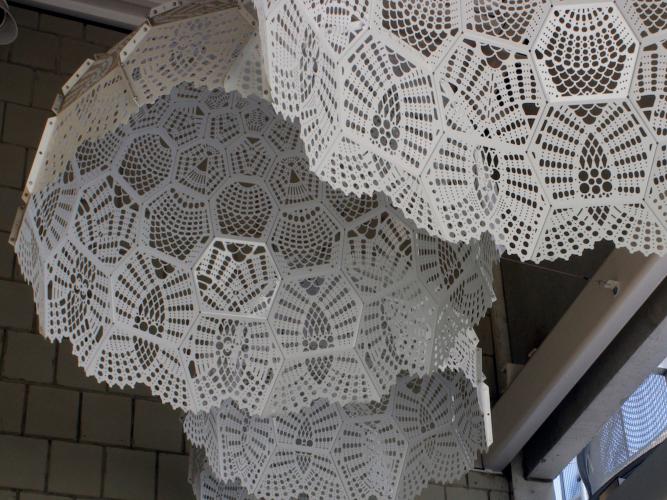 Closeup view of large white doily sculptures hanging from a ceiling.