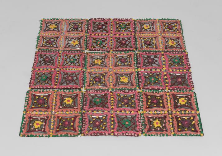 Multiple colorful doilies put together to form a quilt-like rug.