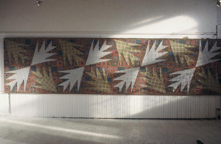 A long wall hanging with a quilt-like pattern and large leaf motifs.