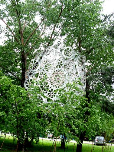 A large white doily installed between trees