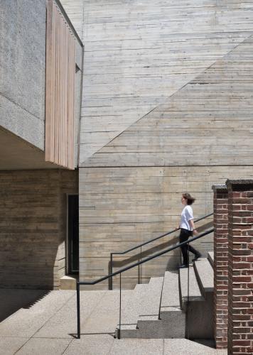 A young woman walks down a flight of concrete stairs outside.