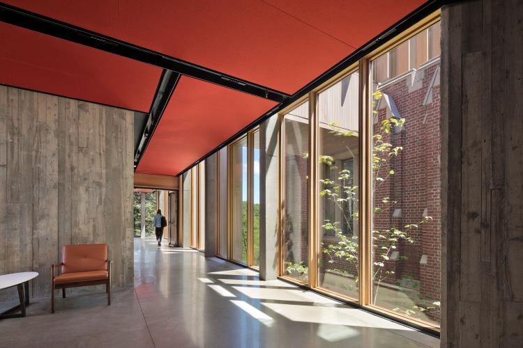 A neutral-colored hallway on the ground floor features a red ceiling and a wall of windows.