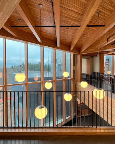 Spherical pendant lights hang from a wood-clad ceiling, past a balcony.