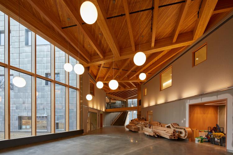 Construction materials inside a finished room with a wall of windows, wood-clad ceiling, and globe pendant lights.