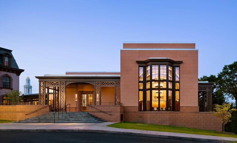 Exterior of a reddish-tan block building at dusk.