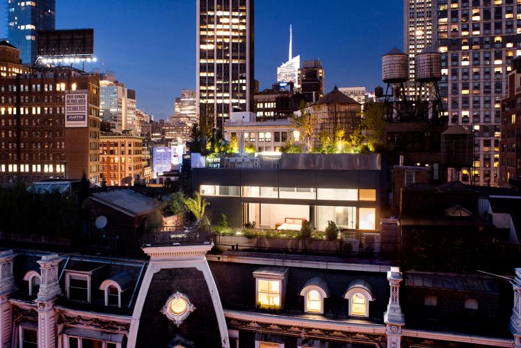 Nighttime view of the rooftop living space and lit rooms on the loft level.